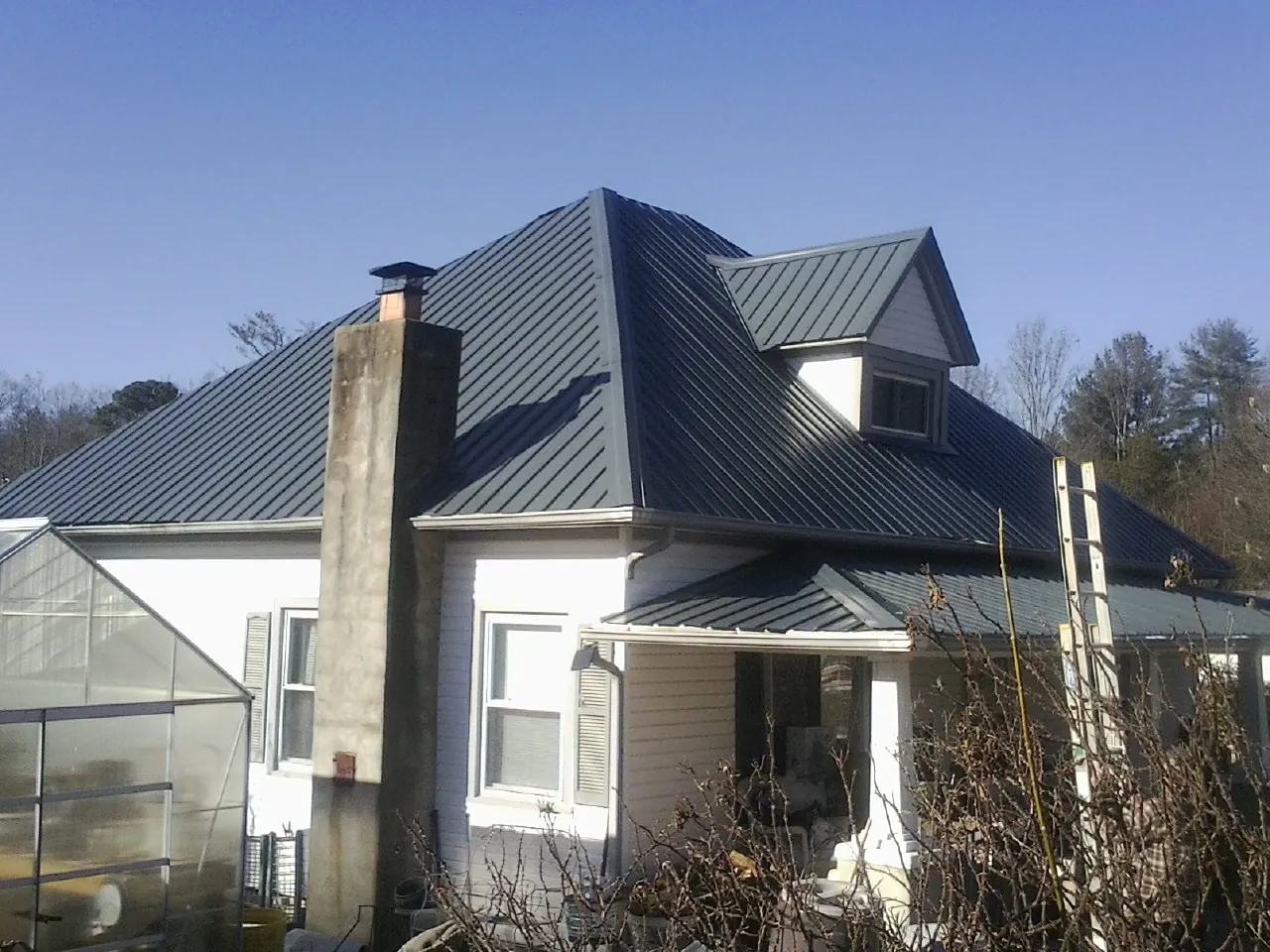 Dark blue standing seam metal roof on a white farmhouse with dormer — Slate & Tile Roof Repair by Roofing Brothers in Cedartown