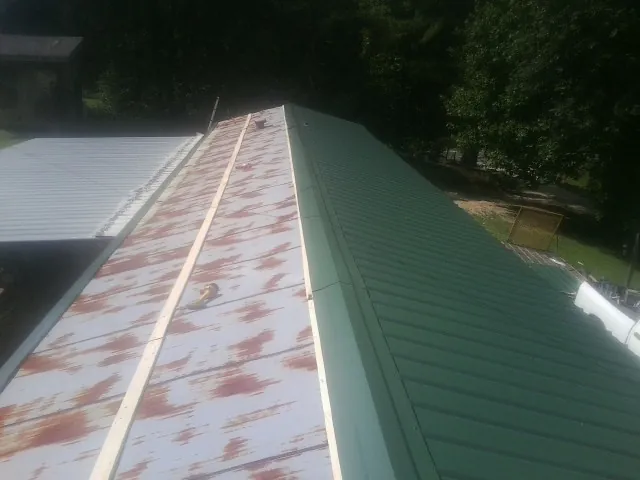 Old rusted panels beside newly installed green metal roofing — Wind Damage Roof Repair by Roofing Brothers in Cedartown