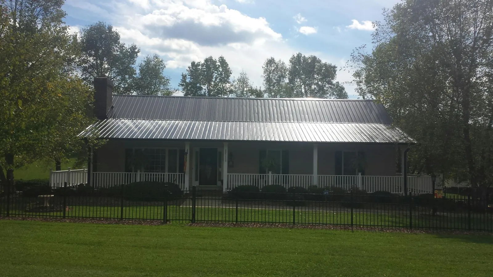 Gray metal roof on a brick ranch with a full width front porch — Gutter Guard Installation work by our crew in Cedartown