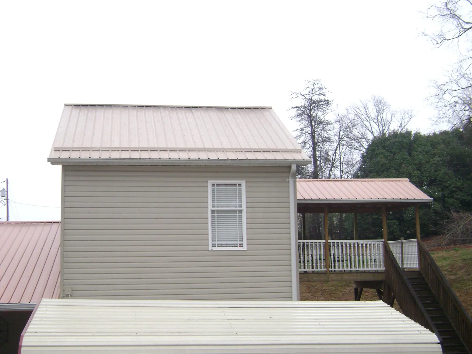 Tan metal roofs on a two story addition and attached porch, from a Roof Replacement job in Cedartown