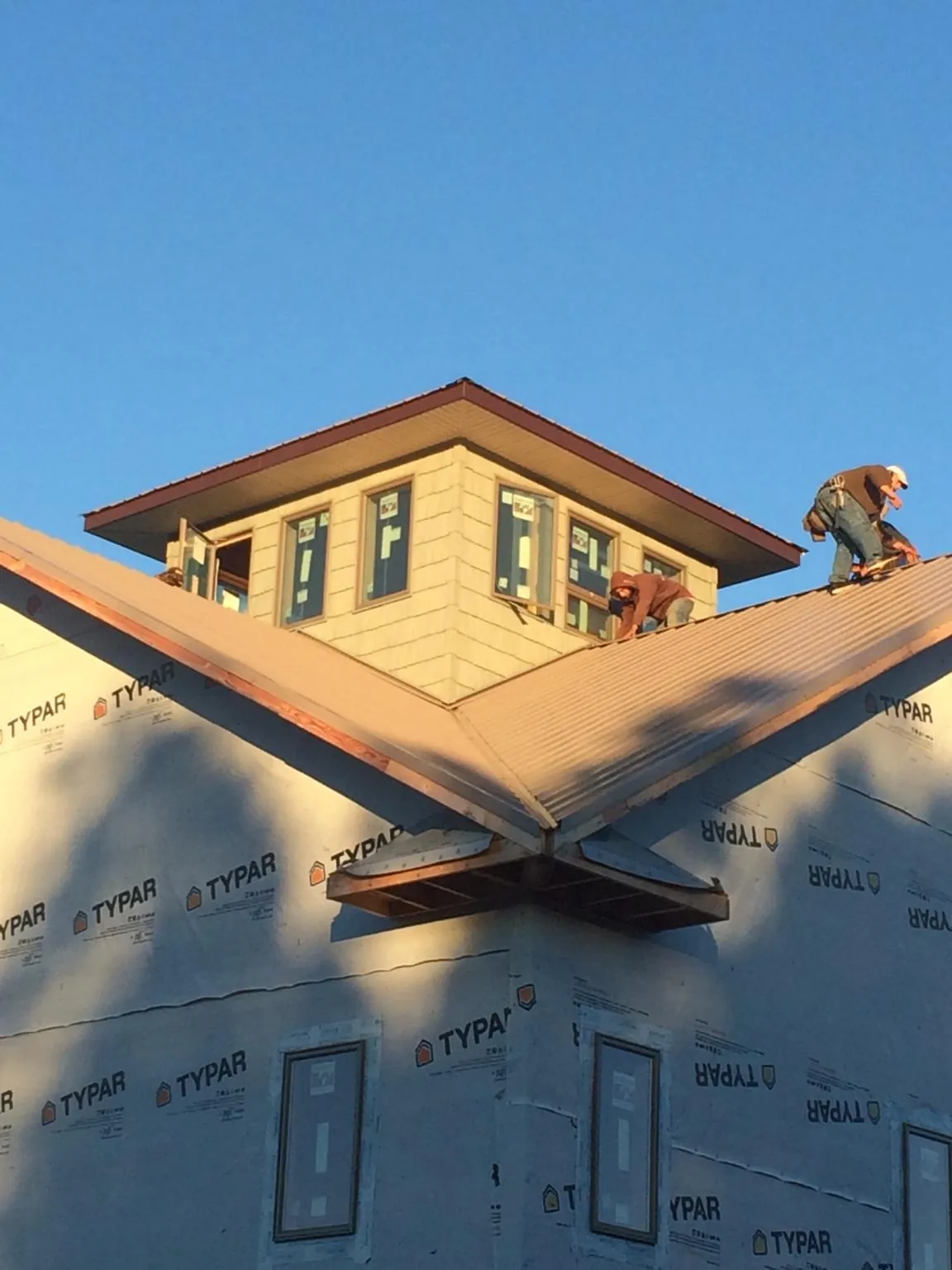 Roofers working around a rooftop cupola on a new metal roof at sunset — Roof Waterproofing in Cedartown by Roofing Brothers